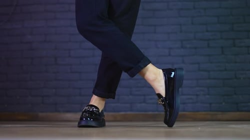 Female model's legs wearing blue fashionable jeans and low-heeled shoes.