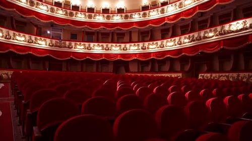 Beautiful theater in red colors indoors. Spacious hall with vacant seats in opera house.
