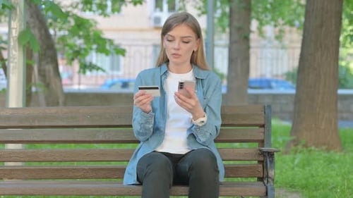 Woman Shopping Online with Phone while Sitting on Bench in Park
