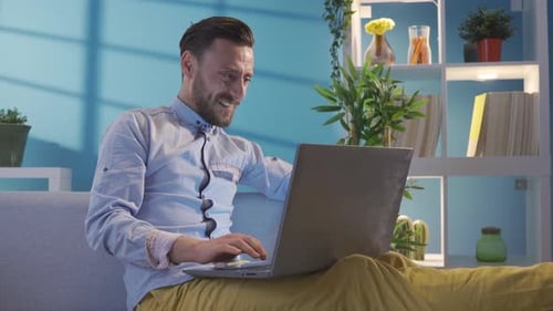 Smiling Man Working on Laptop at Home