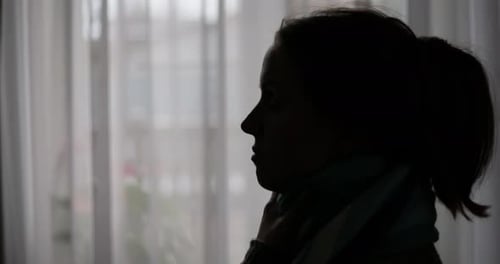 Silhouetted Woman Sprays Medicine into Open Mouth