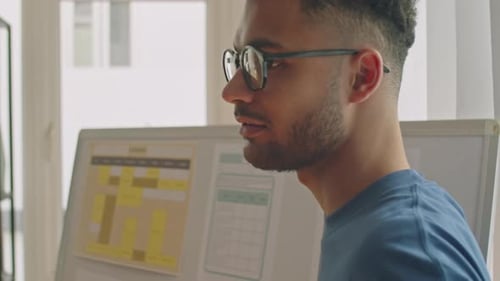 Young Male Teacher Speaking by Whiteboard in Classroom