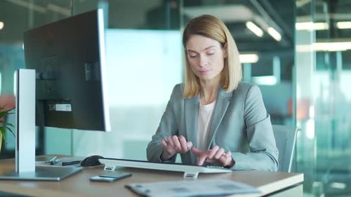 Female office worker in suit working at computer pc in front of monitor correspondence sitting