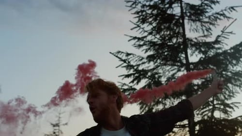 Man Holding Smoke Flare on Mountain Ridge at Sunset