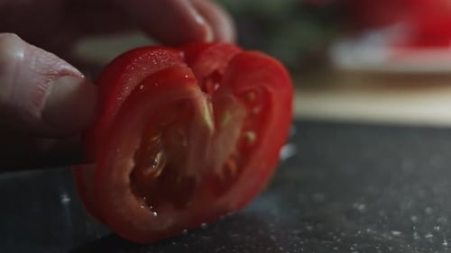 Sharp Knife Slicing a Red Tomato