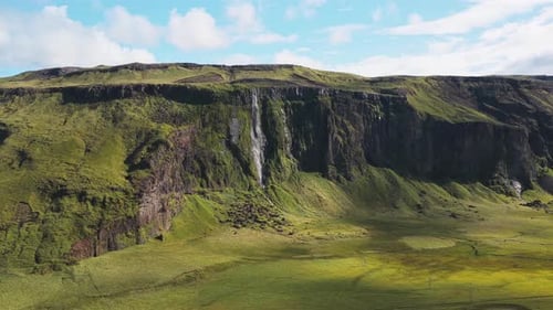 Aerial view of waterfall and green cliffs, Iceland.