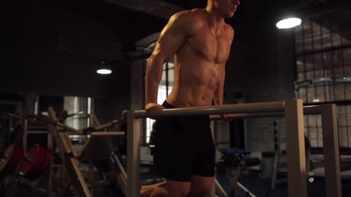 Muscular Man Dips in Dark Gym