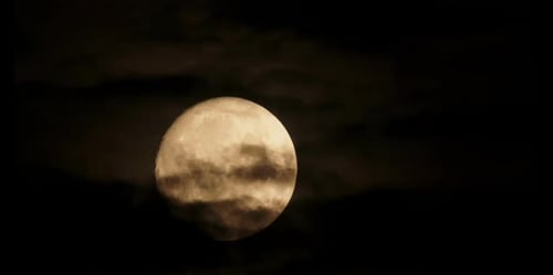 Dramatic Clouds Obscure a Glowing Full Moon