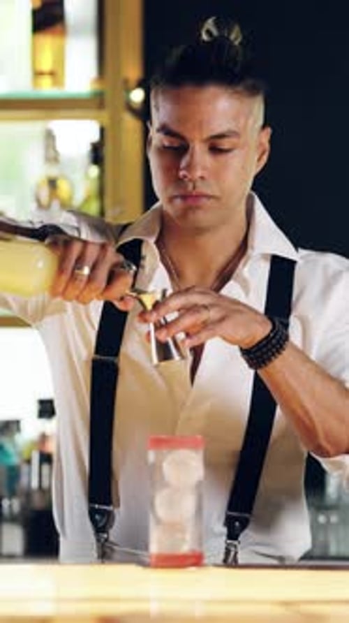 Barman professionnel mélangeant un cocktail alcoolisé avec un jigger