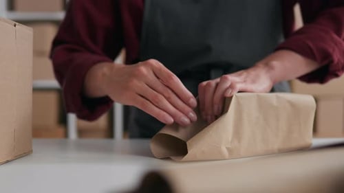 Embalaje del producto, embalaje El trabajador del almacén de papel Kraft en el lugar de trabajo empaca un paquete