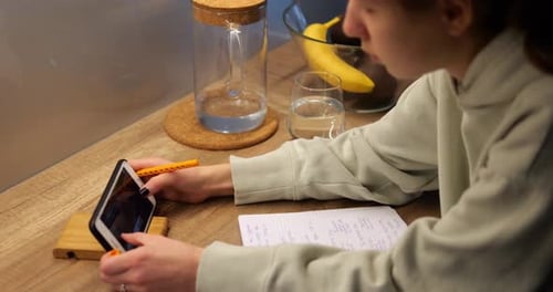 Teenager Using Tablet and Pencil at Wooden Table