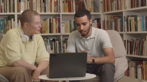 Two Students with Laptop Discussing College Project in Library