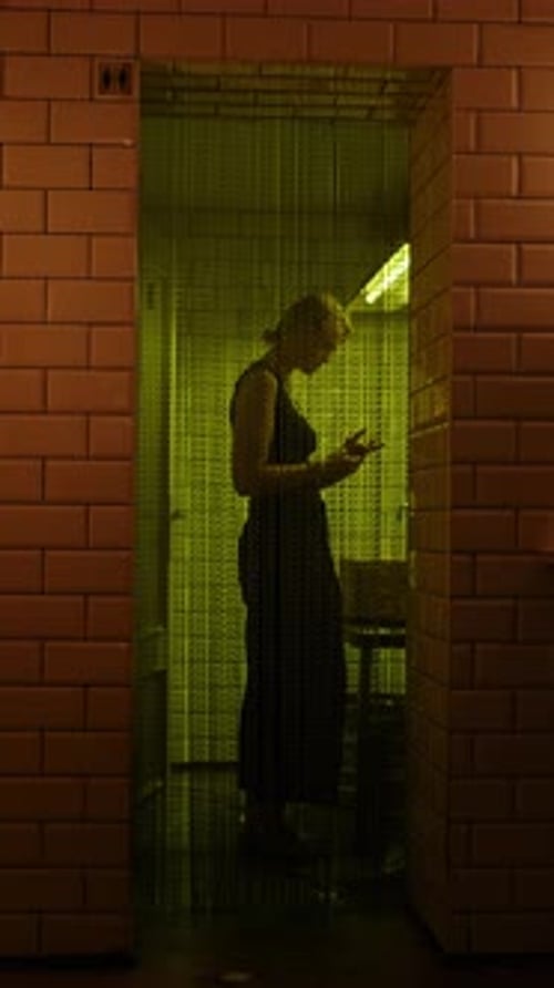 Woman in Dark Restroom Under Yellow Light