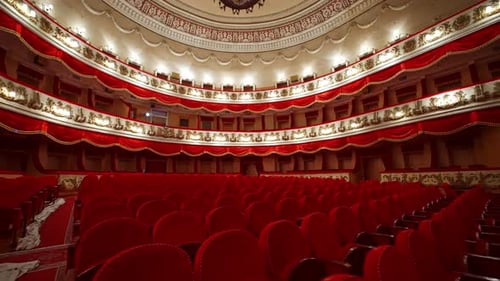 Empty seats in the auditorium of the opera house. Beautiful theatrical hall with rows of red chairs.