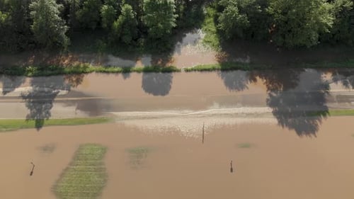 4k aerial top down view rotating around flood water going over a road with rippling water