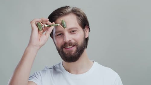 Smiling Man Holds Green Jade Facial Roller