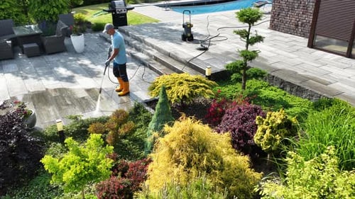 Gardener Uses Pressure Washer to Clean Patio and Maintain Garden