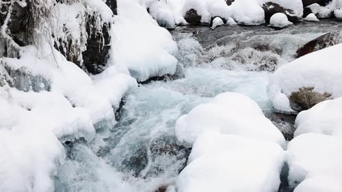 River Stream at Winter Snow Forest in the Mountains