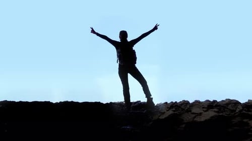 Silhouette of the Woman Raising Her Arms on the Mountain Rocks
