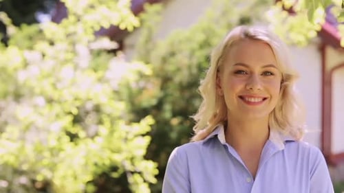 Happy smiling young woman enjoys summer in her beautiful garden home