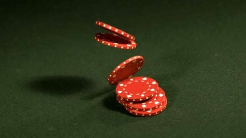 Slow motion cascade of poker chips spilling onto a green felt table