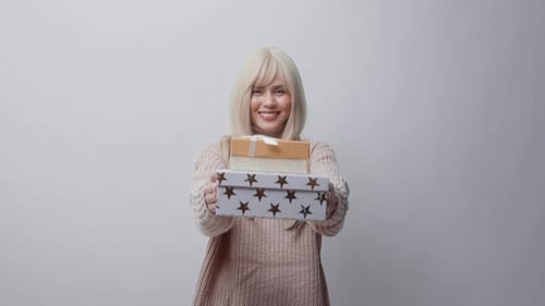 Porträt einer kaukasischen jungen Frau im Pullover mit Geschenkschachtel