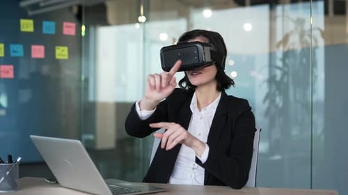 Businesswoman in formal attire uses virtual reality headset in office, interacting with technology