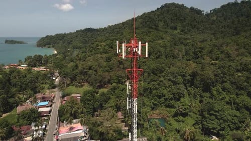 Aerial slow orbit drone shot of a red and white telecommunications tower on a tropical Island in Th