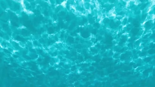 La surface de l'eau turquoise vibrante avec des reflets de lumière crée une ambiance apaisante