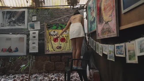 Beautiful artwork hangs on the walls, and a girl works in the background.