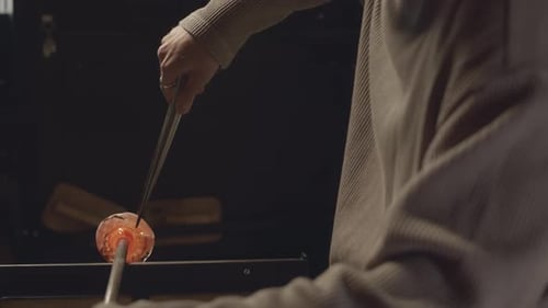 Artisan Glass Blower Shaping Molten Glass in Workshop