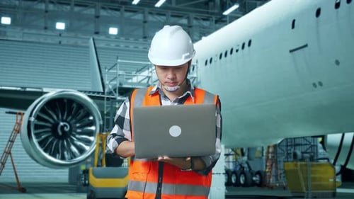 Asian Male Engineer Working On A Laptop While Aircraft Maintenance