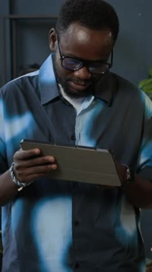 Vertical of Gen Z Colleagues Discussing Project Plan Using Tablet in Office