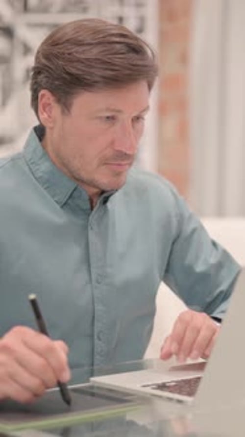 Man uses graphics tablet in the office at desk