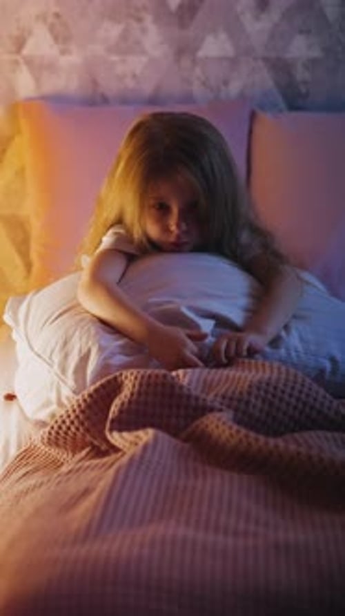Offended Girl Sits Holding Pillow on Bed Near Play House