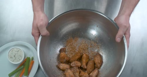 Male Chef Hands Coating Uncooked Buffalo Chicken Wings in Spice and Sauce