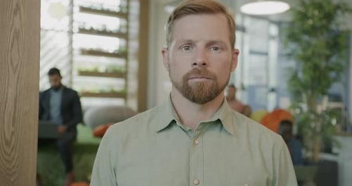 Slow Motion Portrait of Serious Young Businessman Standing in Modern Coworking Office and Looking at