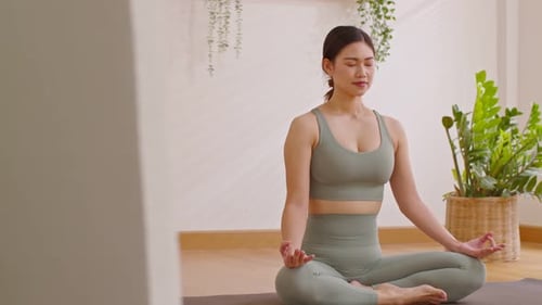Woman Meditating in a Lotus Position Indoors