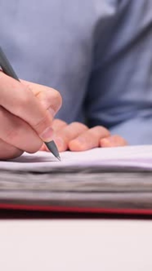Vertical Video Office Worker Writing Notes on Paper in a Binder at Night