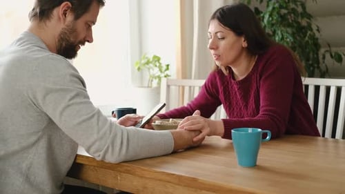 Affectionate Couple Sharing Phone at Wooden Table