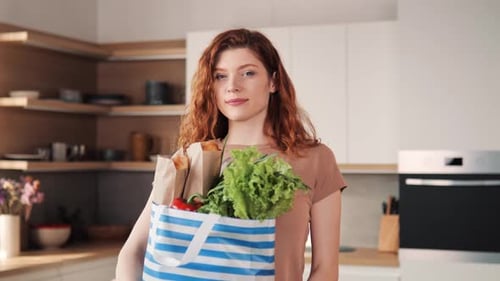 Confident Smiling RedHaired Woman with Eco Products in Kitchen