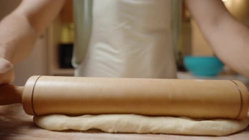 Woman Prepares Dough Using a Rolling Pin in Kitchen