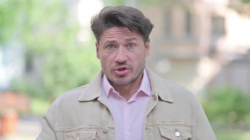 Man Speaking and Pointing to Camera Outdoors