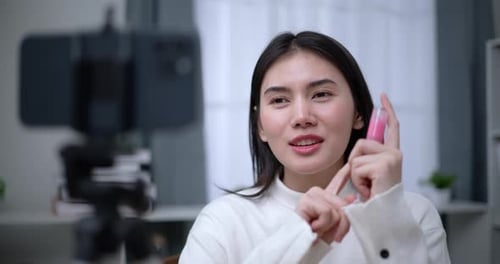 Young Woman Applies Lip Gloss for Online Tutorial