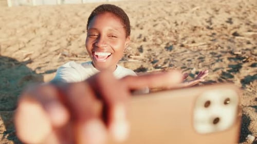 Joyful girl taking selfies on the beach on a sunny summer day