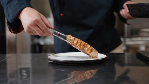 Chef Puts Finished Beef Steak From Pan Onto a Plate in a Restaurant Kitchen