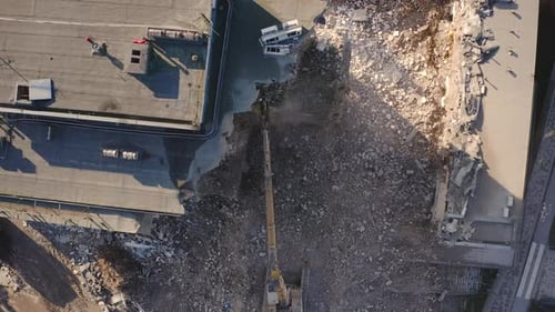 Aerial view of an Excavator drilling and demolishing the concrete wall of building or apartment