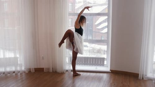 Young Woman Ballerina Warming Up in the Studio Standing By