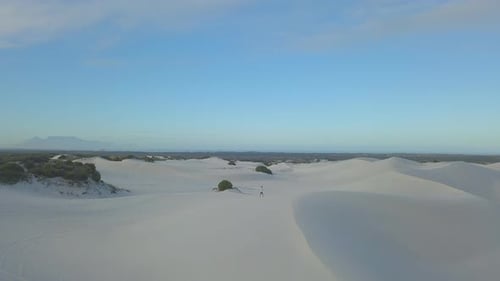 Aerial of man running on sand dunes in South Africa at sunset