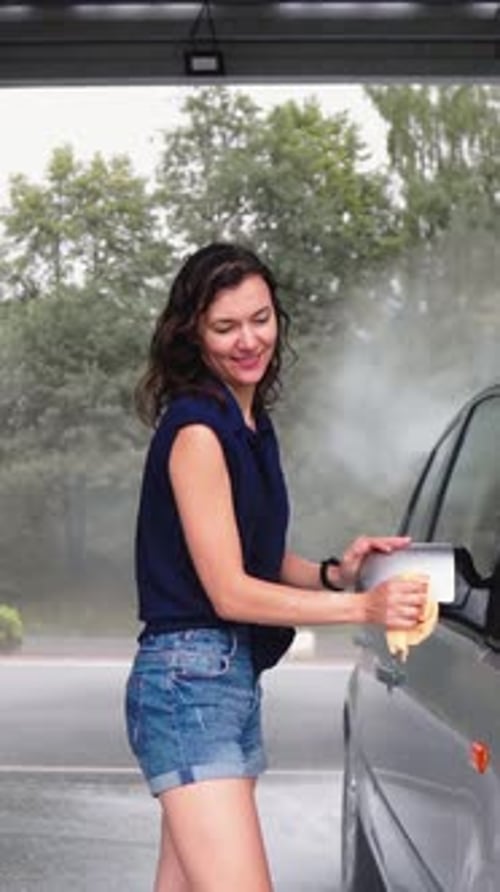 A Woman Enthusiastically Washing Her Car at a Vibrant Car Wash Station Enjoying the Fresh and